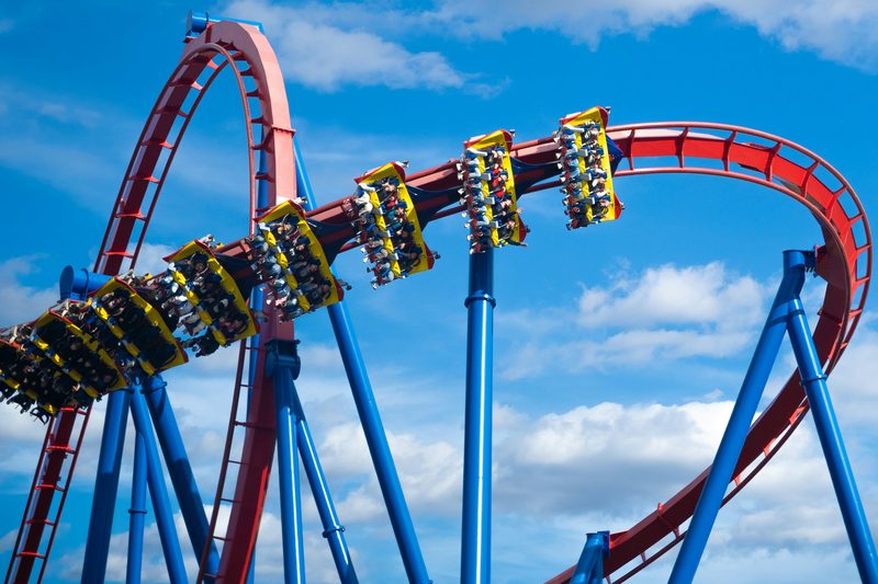 Rollercoaster with riders at a theme park against a blue sky