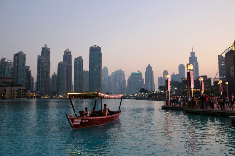 Traditional abra boat on Dubai Creek at dusk with the city skyline behind